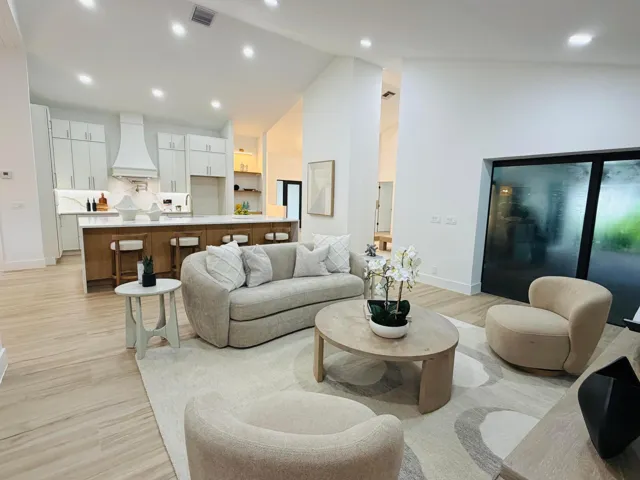 Vaulted ceiling with recessed lighting, wood-finish flooring, full-height sliding glass doors, kitchen island with seating, and integrated kitchen appliances