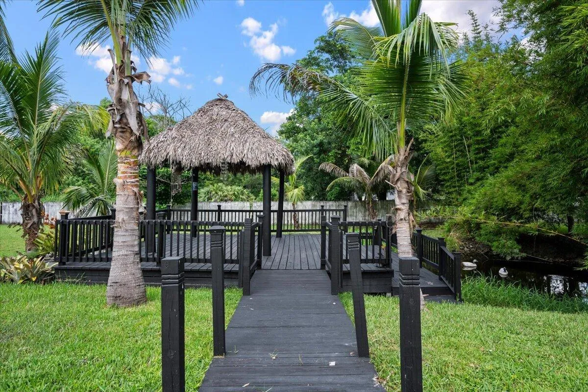 Your own tropical escape awaits just steps from home, where a palm-lined walkway leads to a peaceful waterfront tiki hut surrounded by lush greenery. Imagine morning coffee by the pond, afternoon shade beneath the palms, or evening drinks as you unwind in a setting that makes every day feel like a Florida getaway.