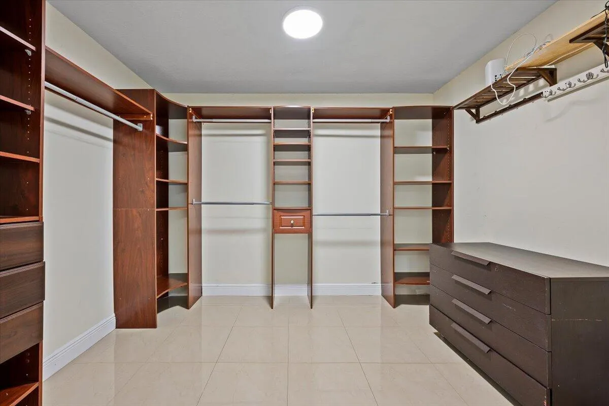 A place for everything, and room to make it yours. This spacious walk-in closet offers custom built-ins, generous hanging space, shelving and drawers to keep everyday living beautifully organized.