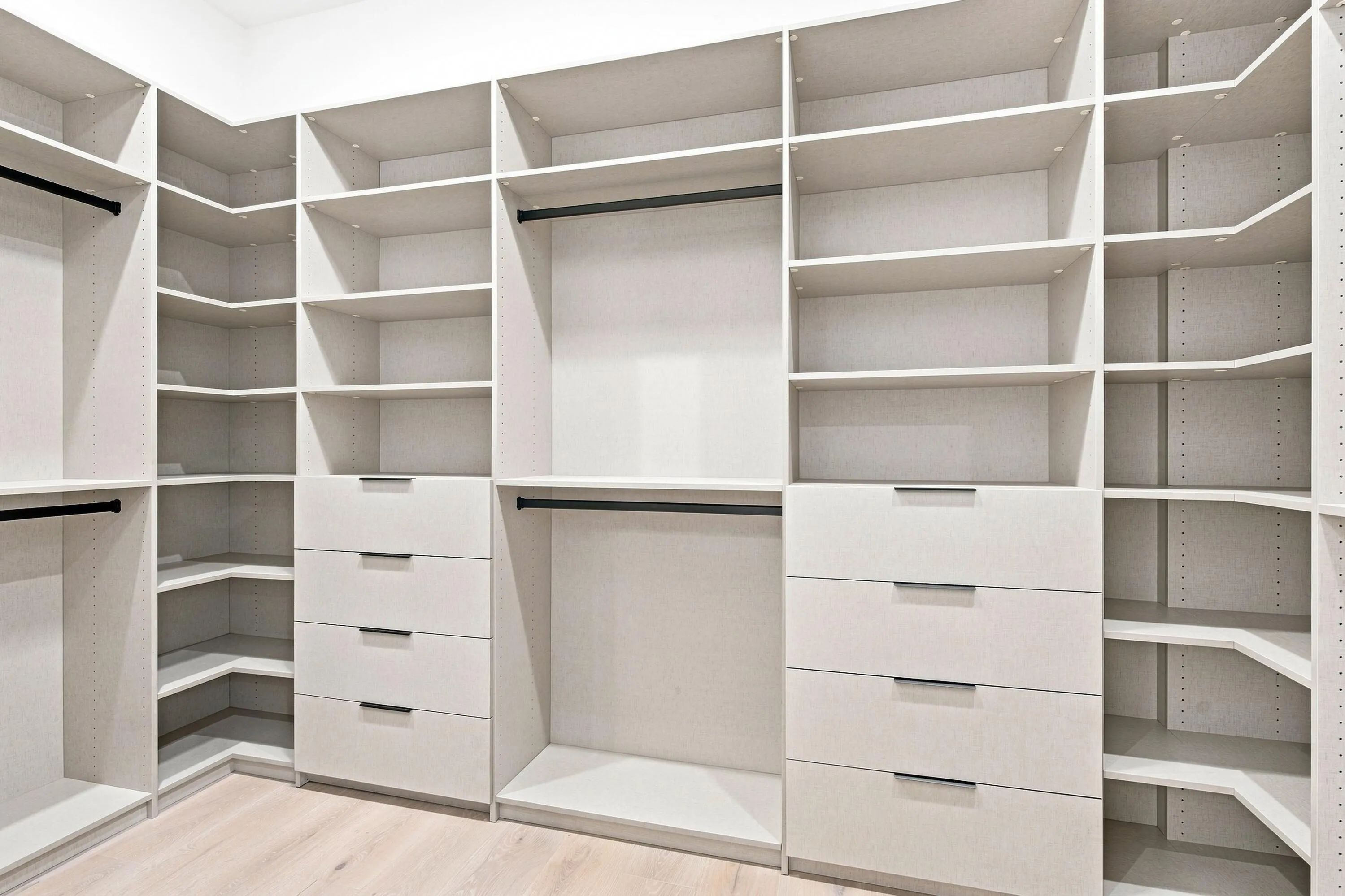 Custom closet system featuring multiple integrated shelving units, drawers with contemporary hardware, and dedicated hanging rods