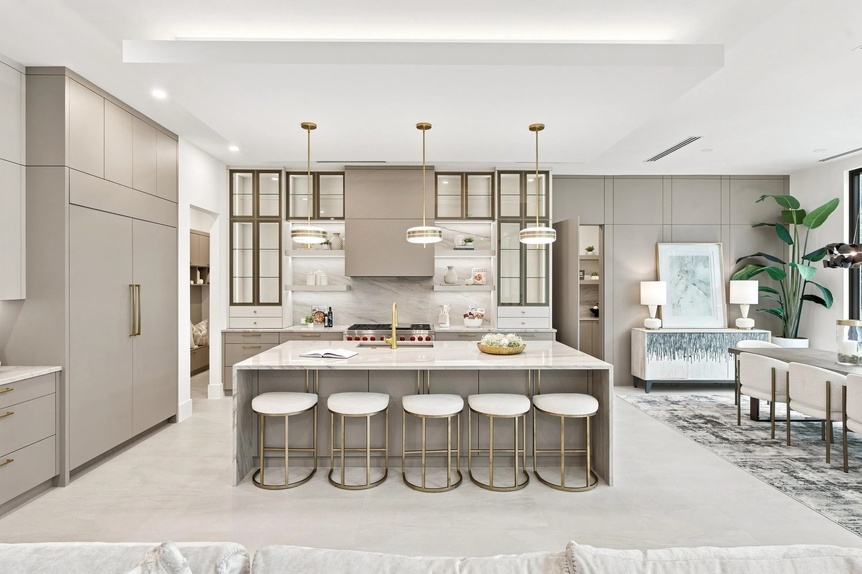 Gourmet kitchen featuring a waterfall island, integrated appliances, custom cabinetry, and a built-in range with hood