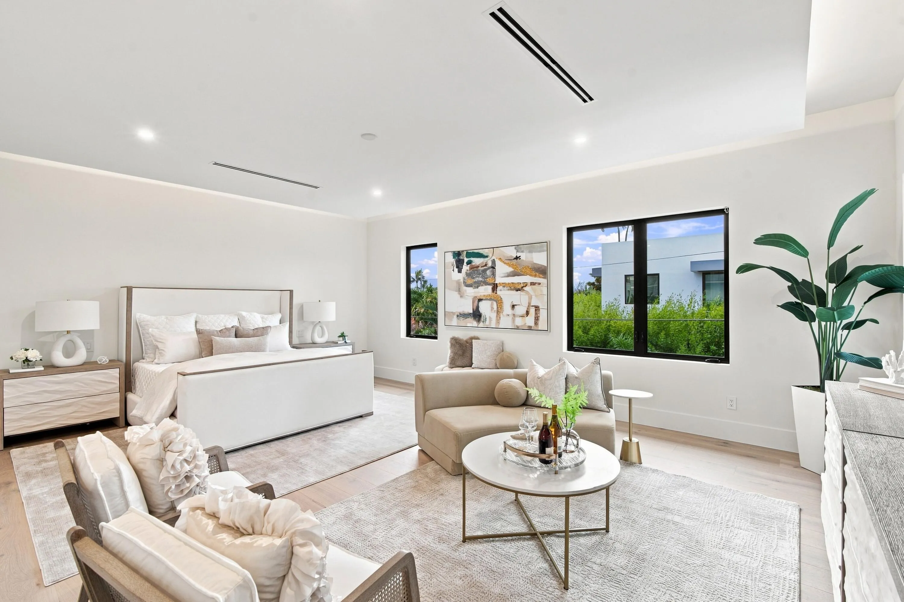 Spacious room with light wood-finish flooring, recessed lighting, and large windows with dark frames