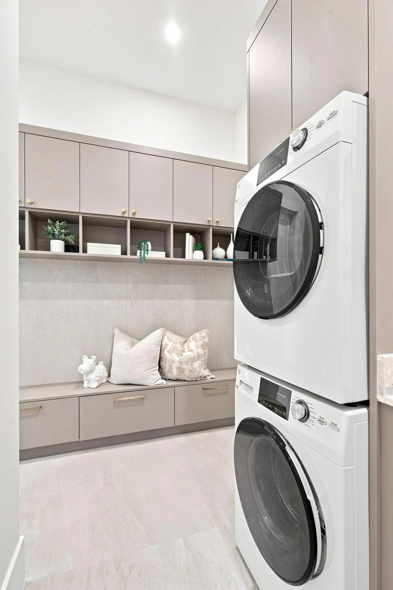 Stackable laundry appliances, integrated cabinetry, open shelving, built-in bench seating, and recessed lighting
