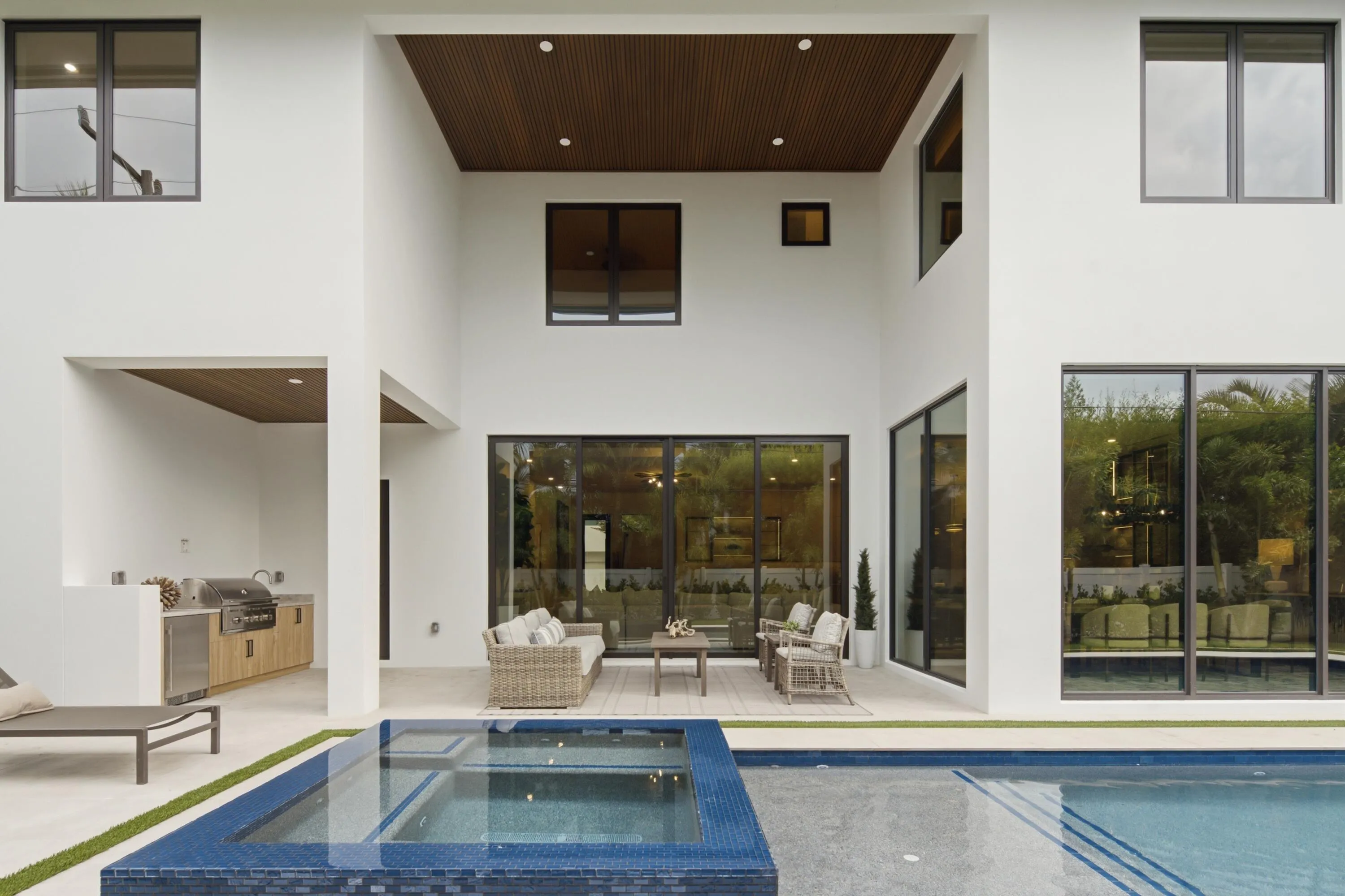 Expansive outdoor living area featuring a built-in outdoor kitchen, integrated swimming pool, and spa with mosaic tile