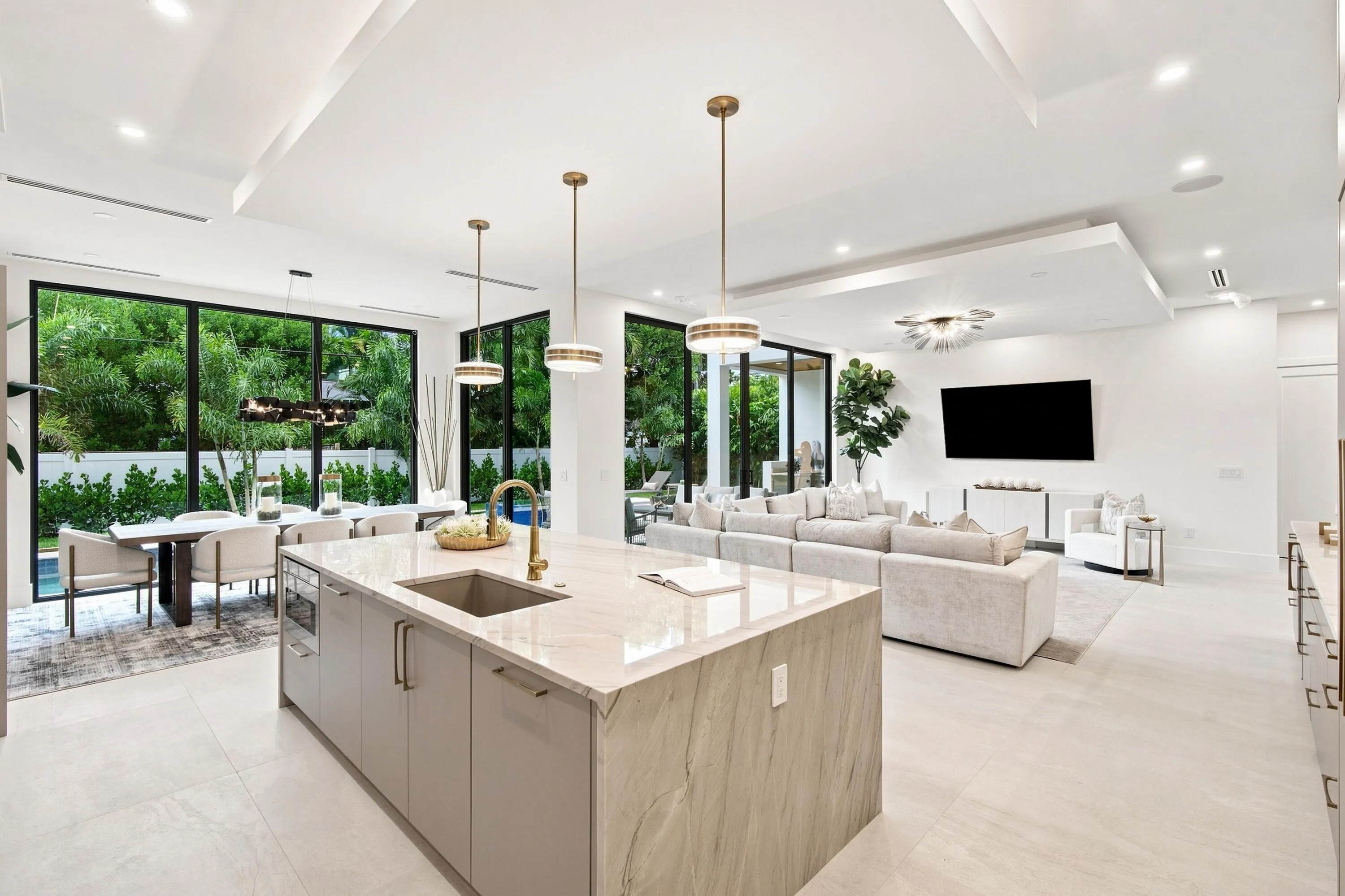 Expansive open-concept living area featuring a large kitchen island with integrated sink, sleek cabinetry, and integrated appliances