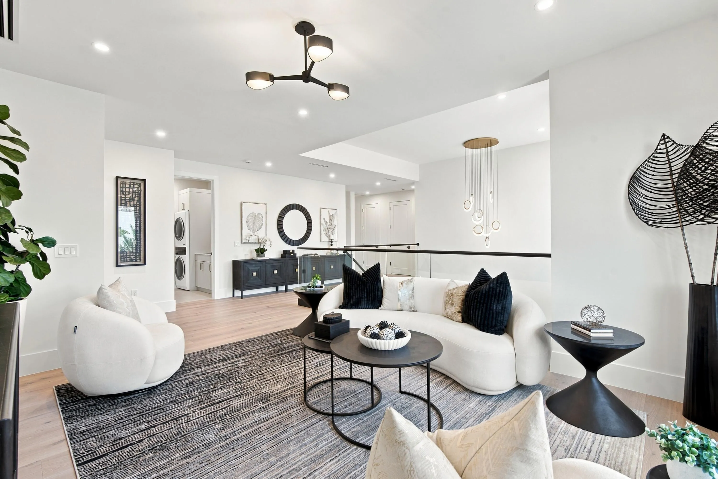 Recessed lighting, wood-finish flooring, contemporary chandelier, glass railing, and built-in laundry appliances