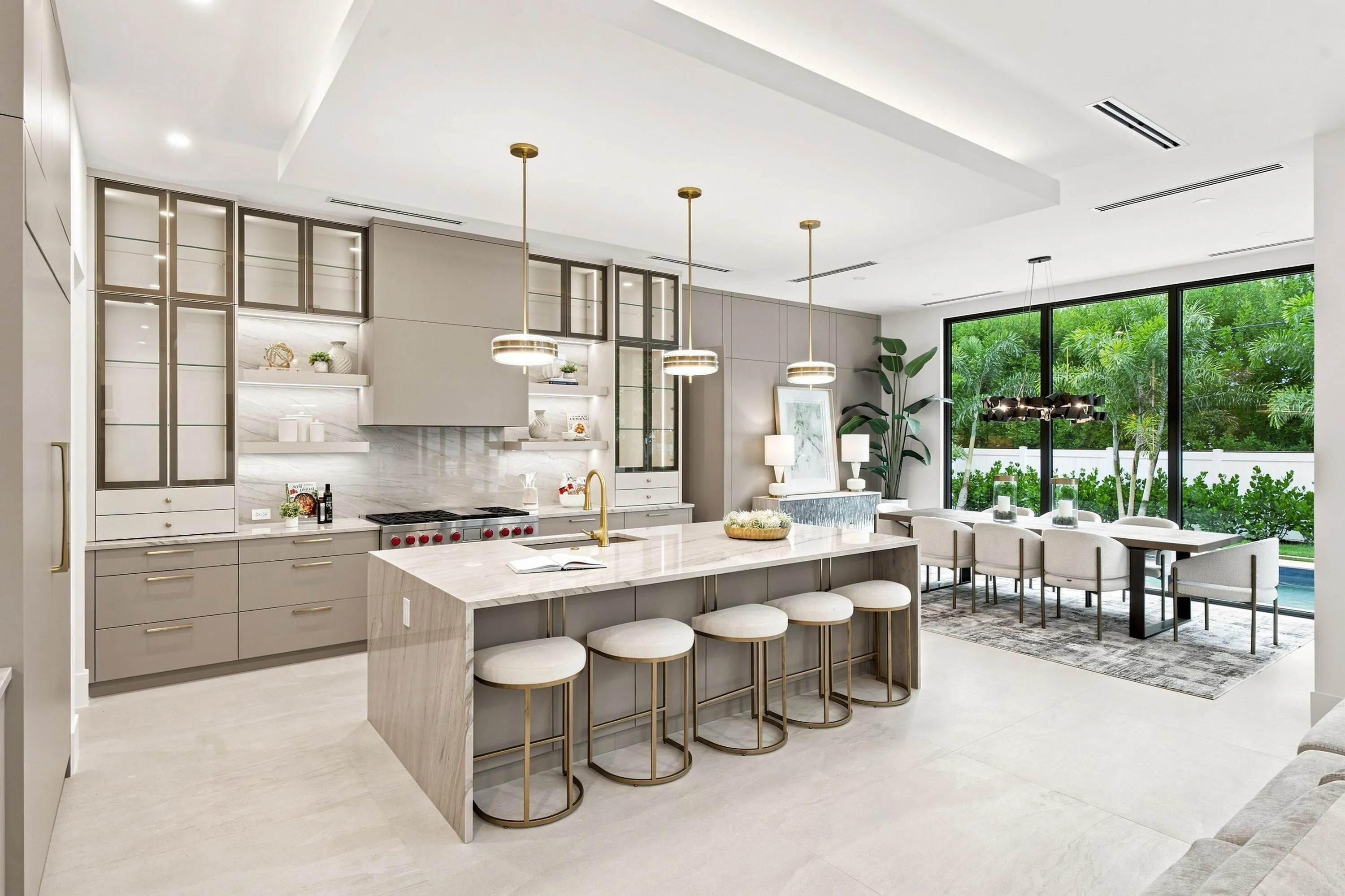 Gourmet kitchen featuring a large central island, integrated appliances, extensive cabinetry with glass fronts, and recessed lighting