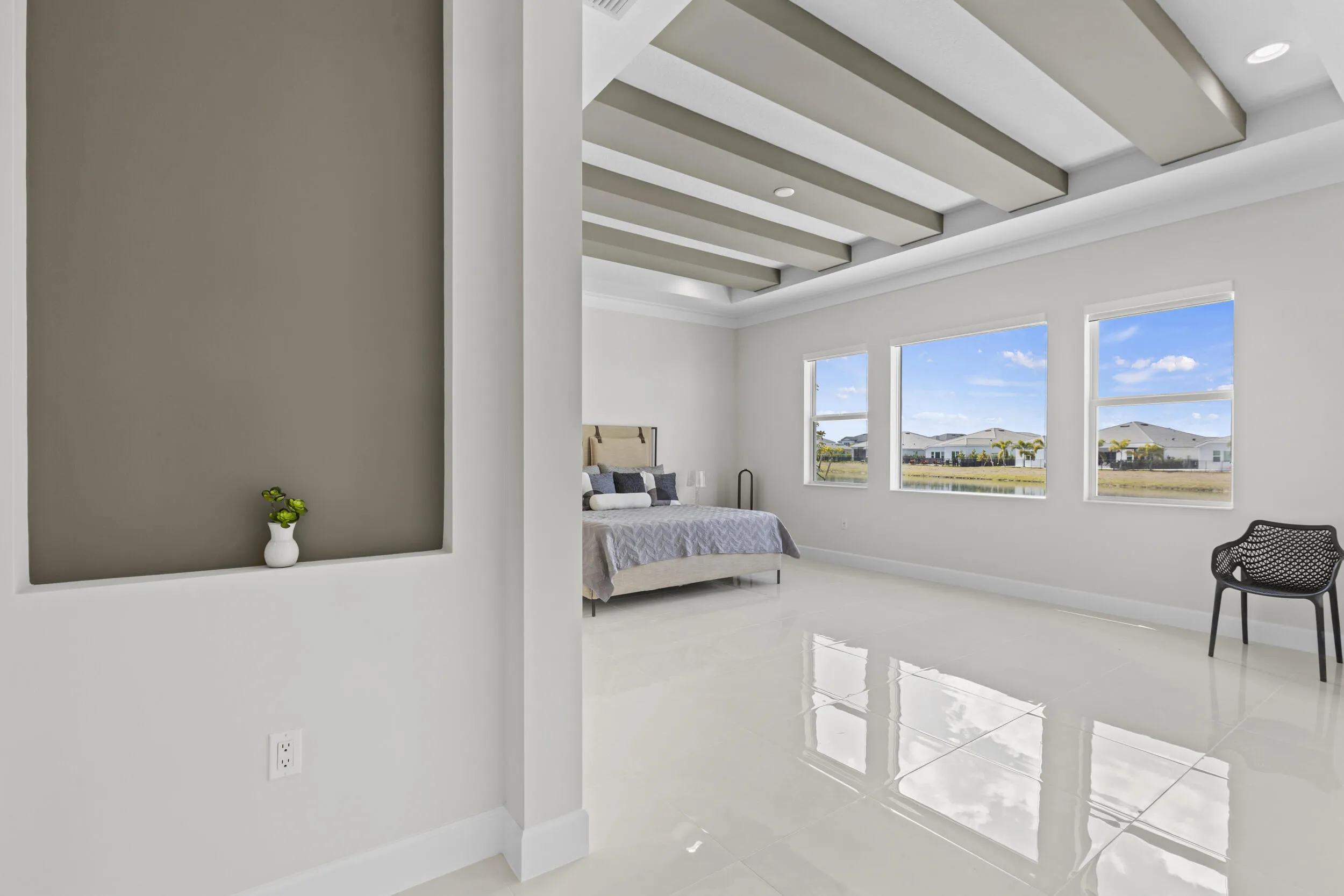 Owner's Suite featuring tray ceiling with decorative beams, large windows, recessed lighting, and tile flooring