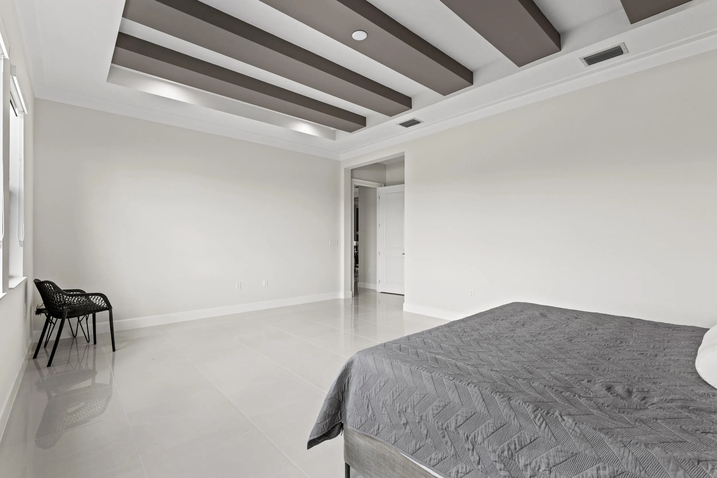 Owner's Suite featuring tray ceiling with recessed lighting and decorative beams, large window, light-toned flooring, and crown molding