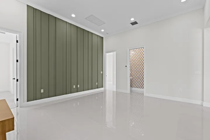 Flex Room with expansive interior space featuring a paneled accent wall, recessed lighting, white tile flooring, and a decorative frosted glass door