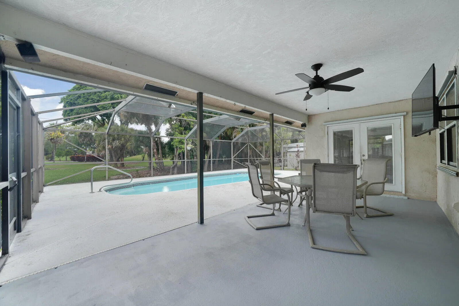 Screened-in patio with an in-ground swimming pool, ceiling fan, and French doors