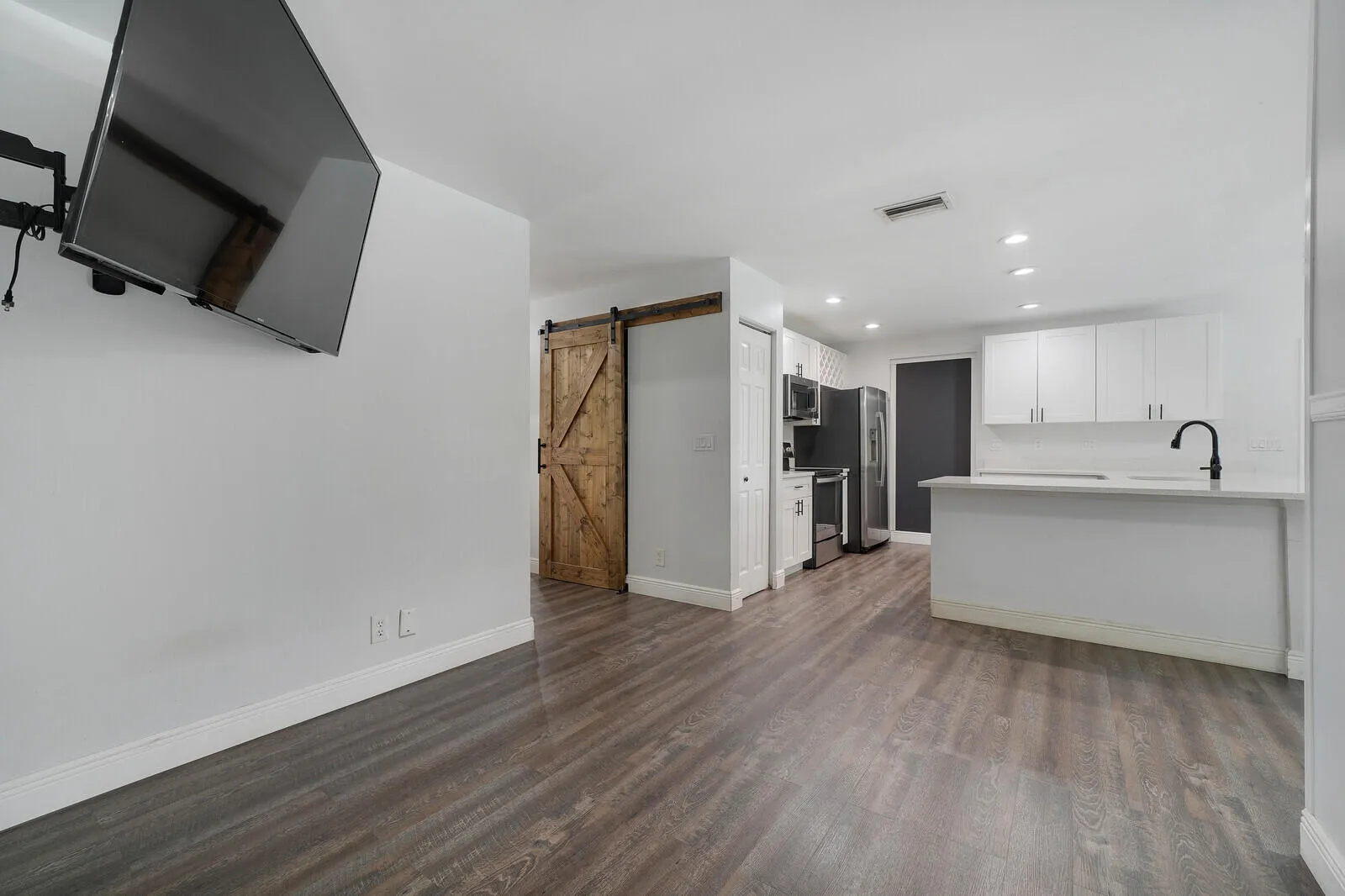 Wood-finish flooring, white walls, and a barn-style door
