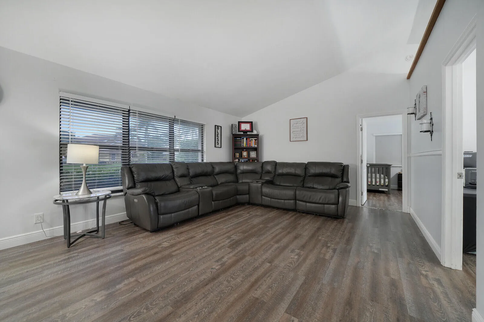 Wood-finish flooring, vaulted ceiling, and multiple windows with blinds