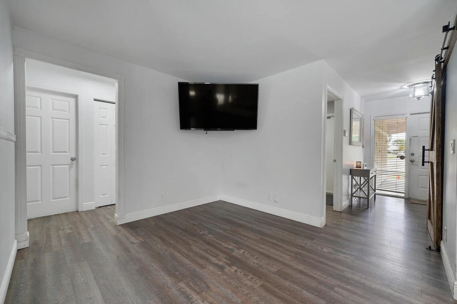 Wood-finish flooring throughout, white walls, and a recessed ceiling light fixture