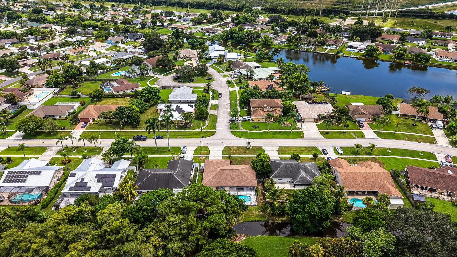 Residential neighborhood featuring single-story homes, mature landscaping, and an expansive lake