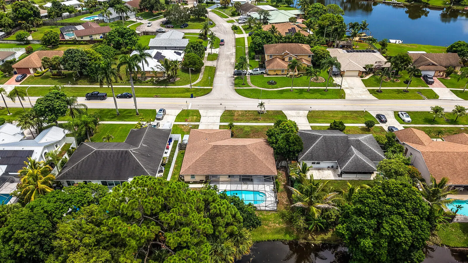Residential street with mature trees and landscaping, featuring a private swimming pool