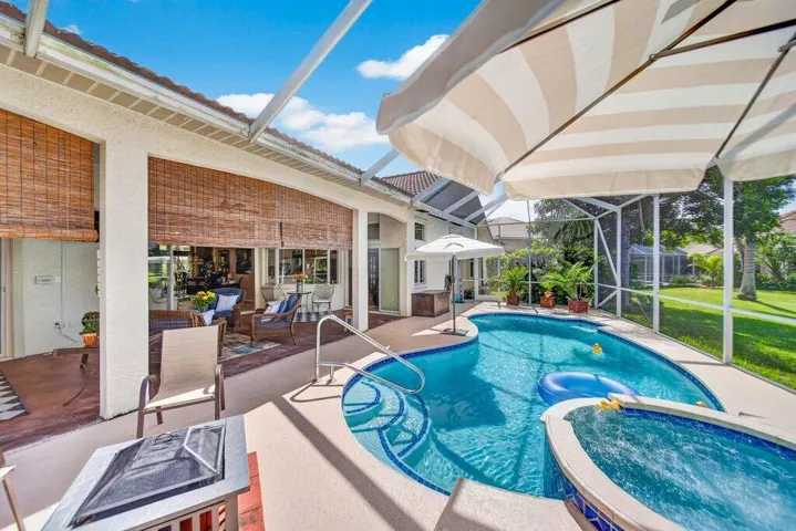 Screened-in patio featuring a tiled pool, integrated spa, and an expansive concrete pool deck