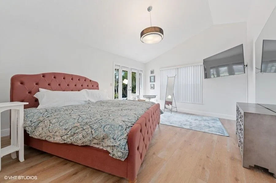 Vaulted ceiling with a flush mount light fixture, light wood-finish flooring, and white walls