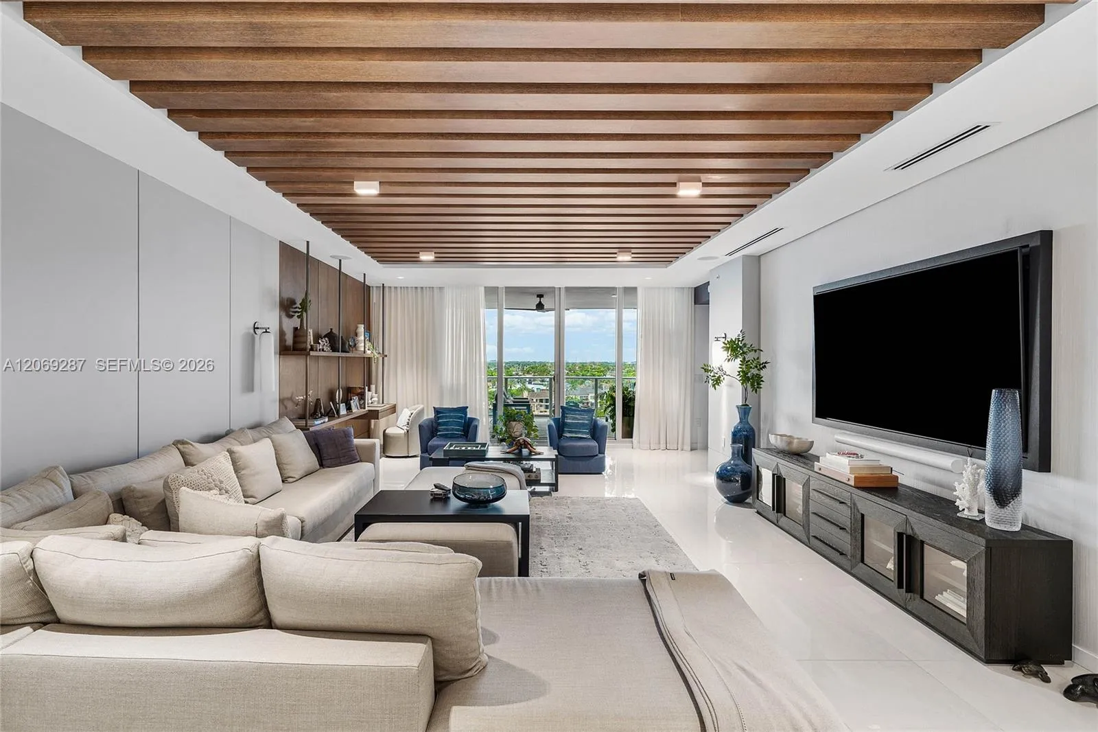 An expansive living room offering panoramic waterfront views and seamless access to the terrace.