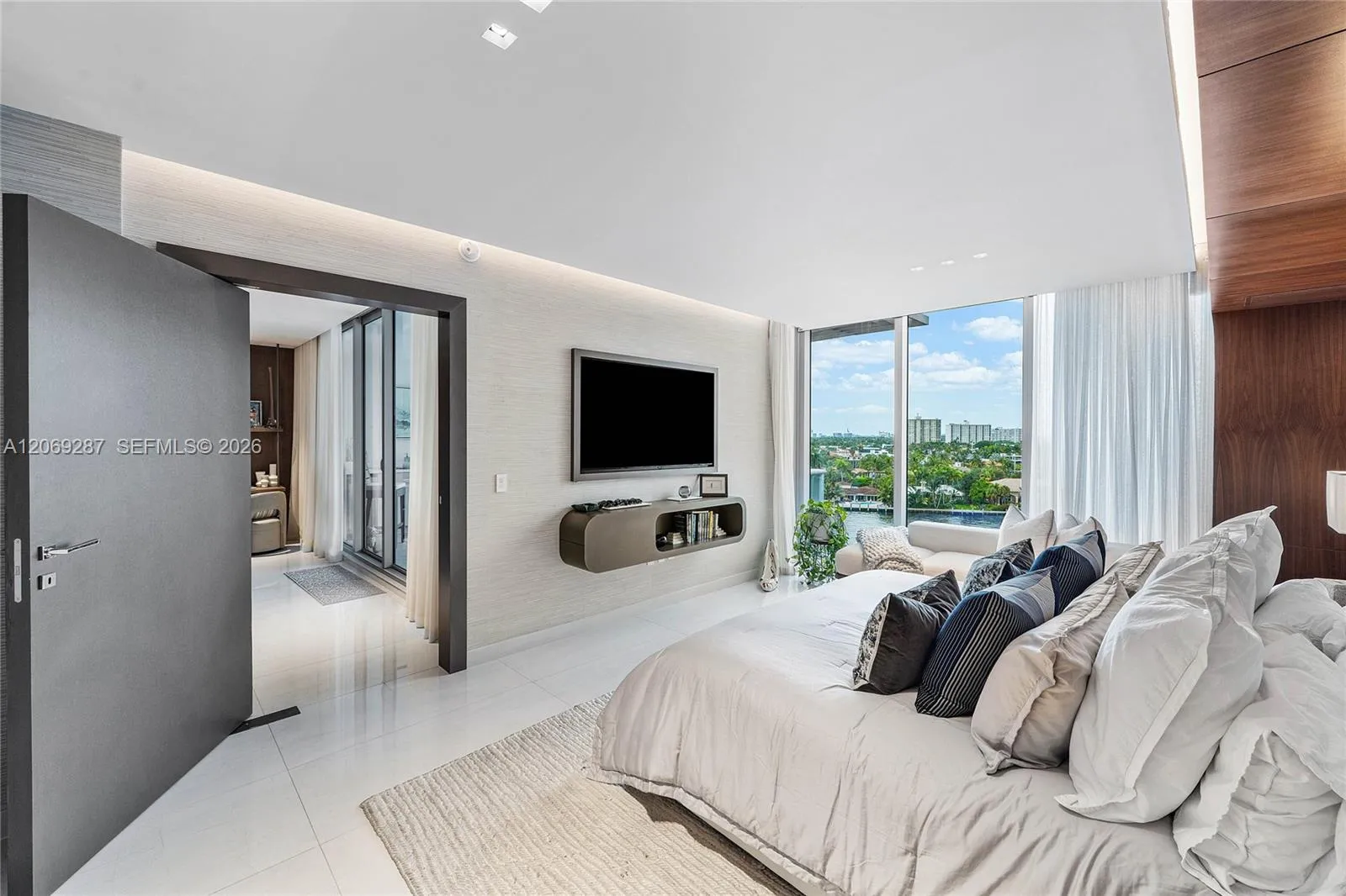 A serene primary suite with floor-to-ceiling glass, private terrace access and captivating waterfront views.