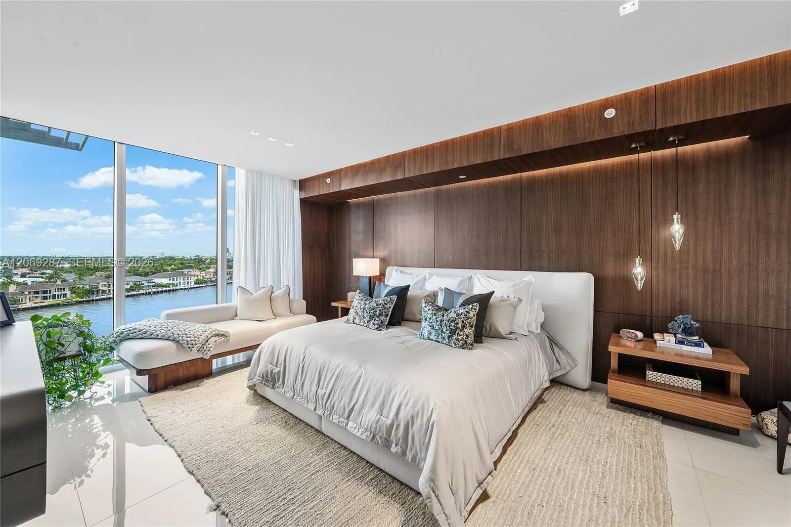 A serene primary suite with floor-to-ceiling glass, private terrace access and captivating waterfront views.