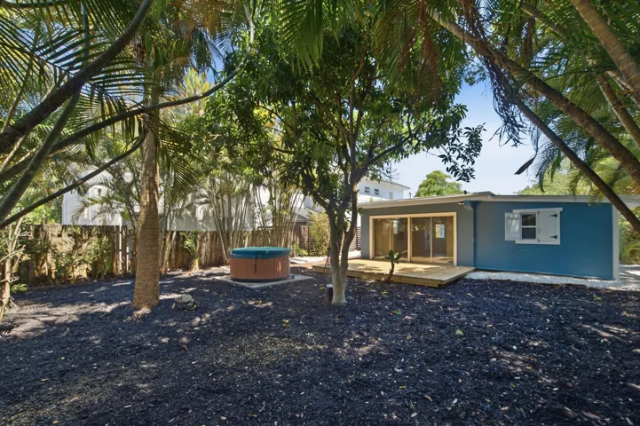 Rear exterior featuring a wood deck, sliding glass doors, a spa, and a stucco finish
