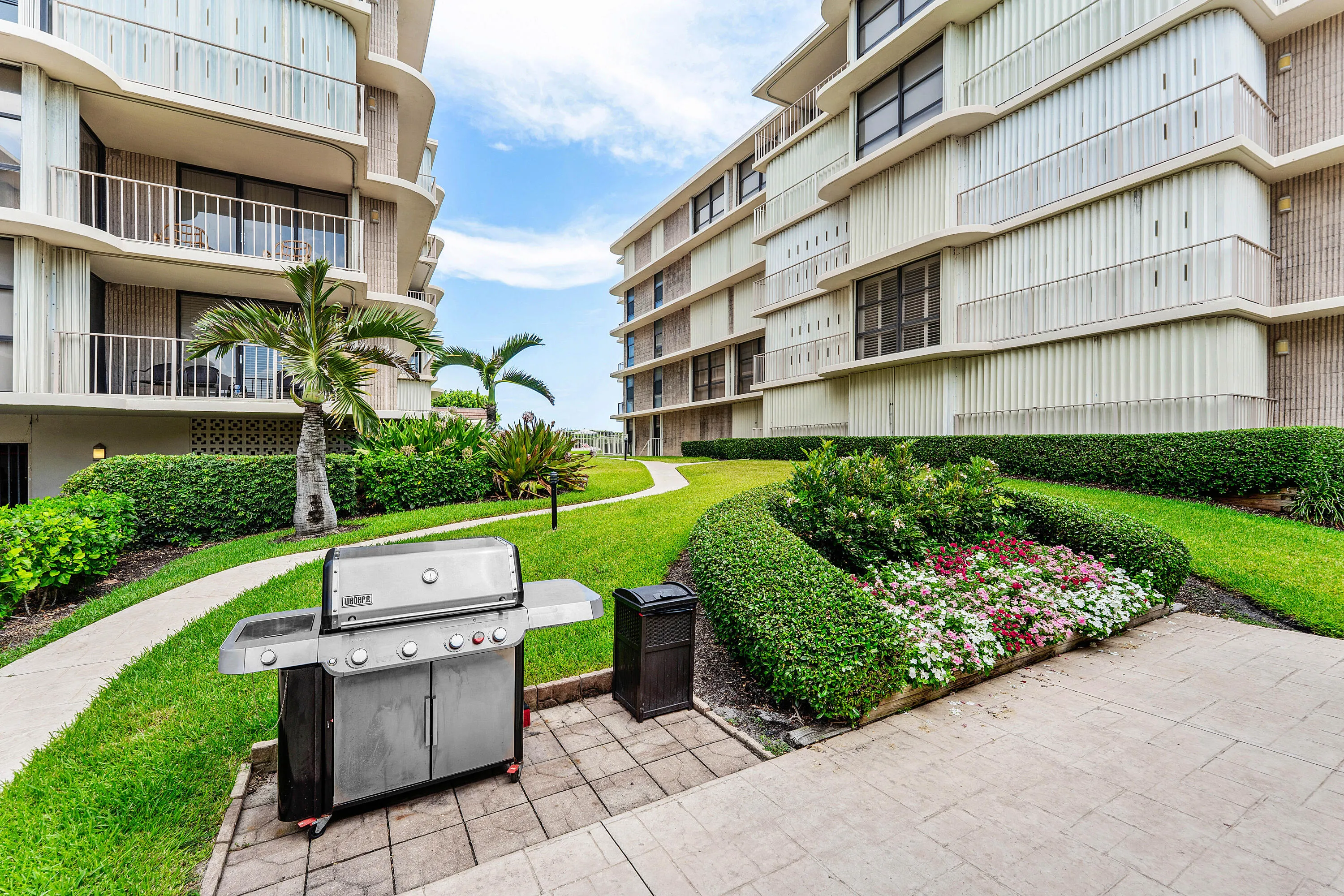 Landscaped grounds featuring a paver patio, grill station, and manicured shrubbery