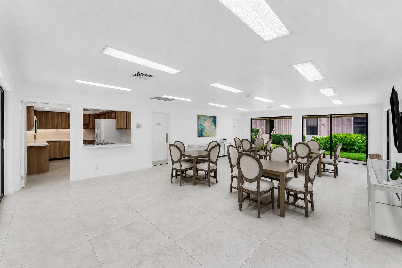 Spacious common area featuring light-toned tile flooring, recessed ceiling lighting, and expansive glass sliding doors