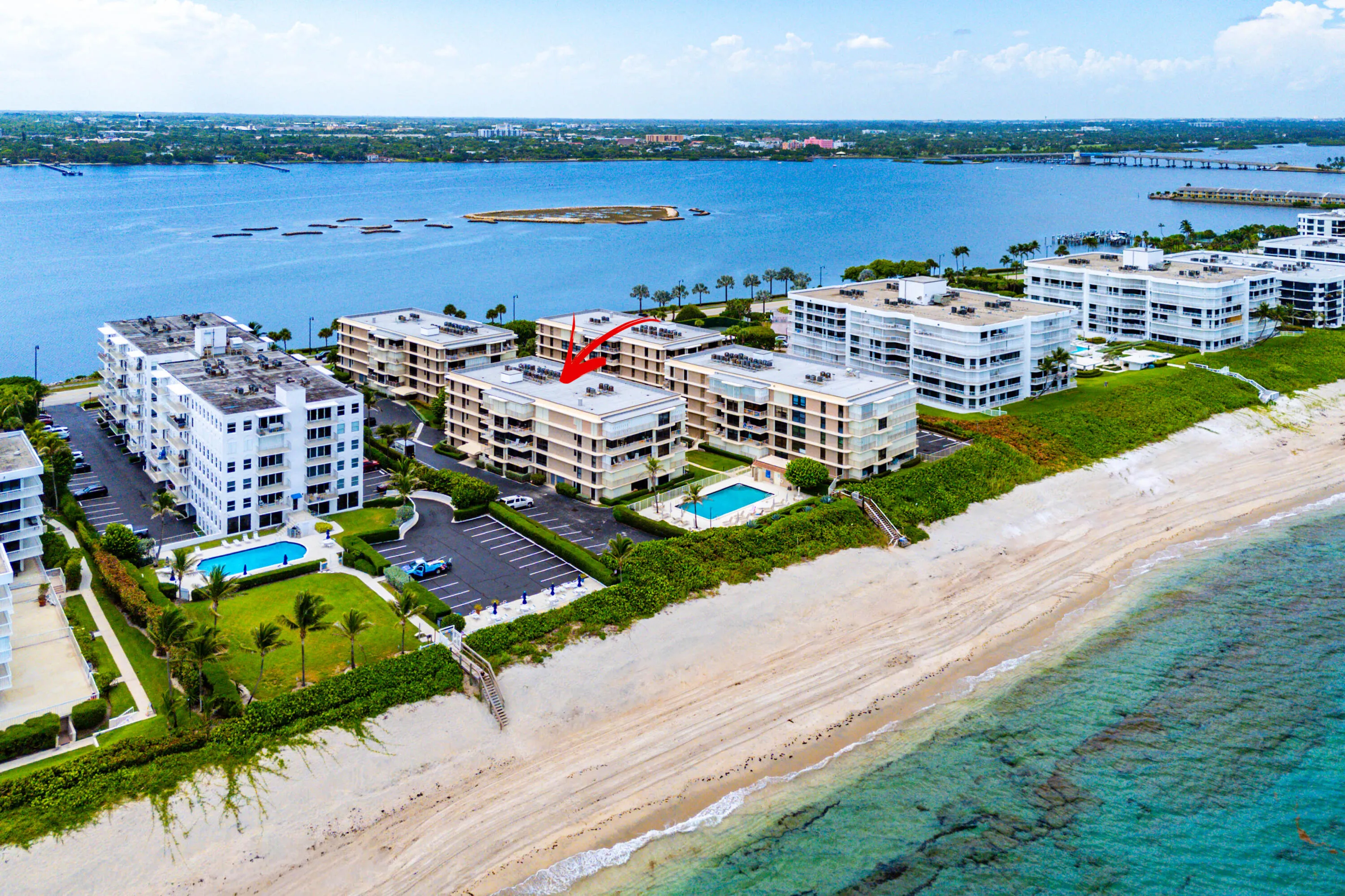 Waterfront condominiums featuring beach access, a swimming pool, and dedicated parking