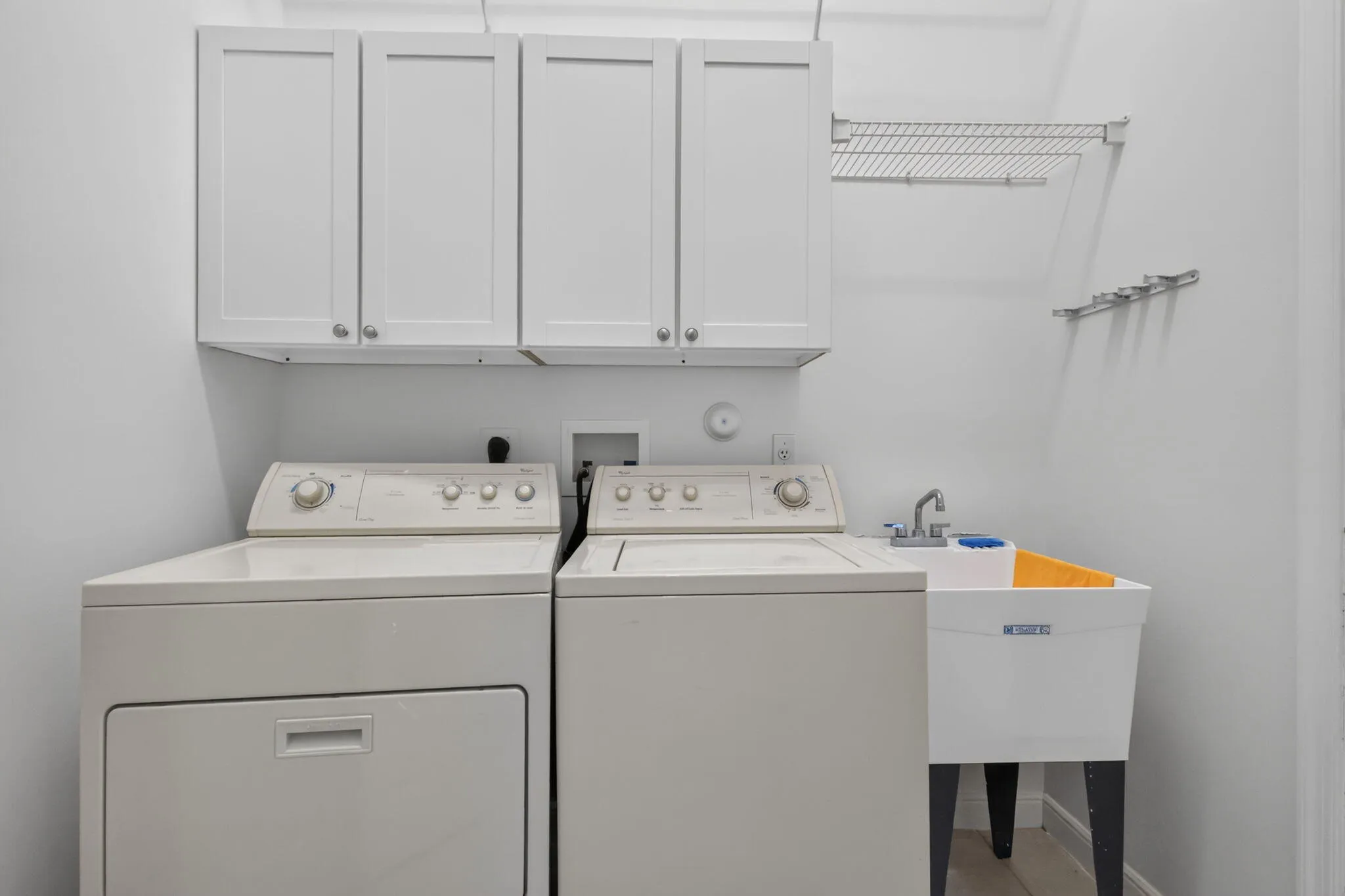 Laundry area featuring upper cabinetry, utility sink, and wall-mounted shelving