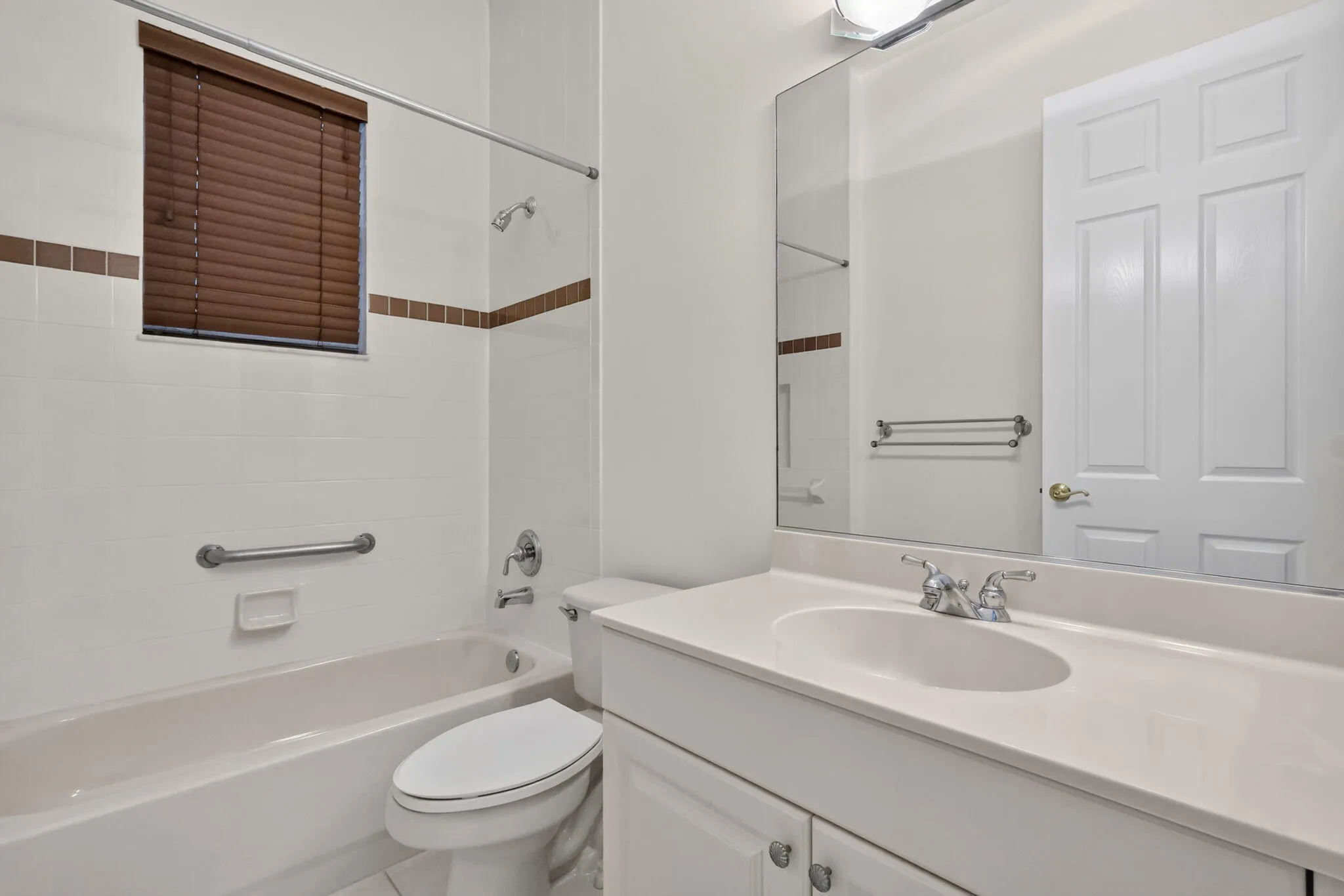 White tiled bath surround with brown accent tiles