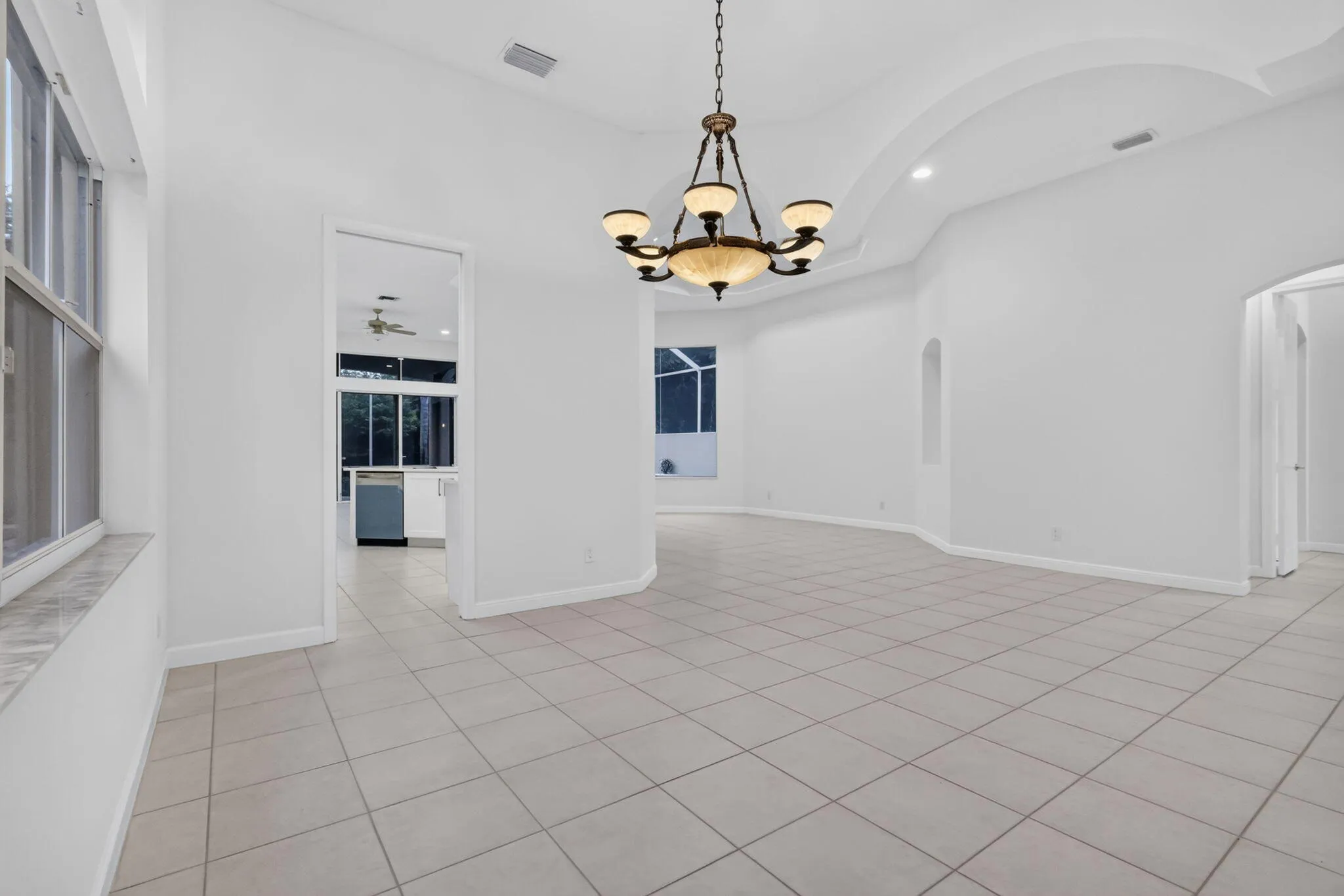 Neutral-toned tile flooring, tray ceiling, and a traditional chandelier