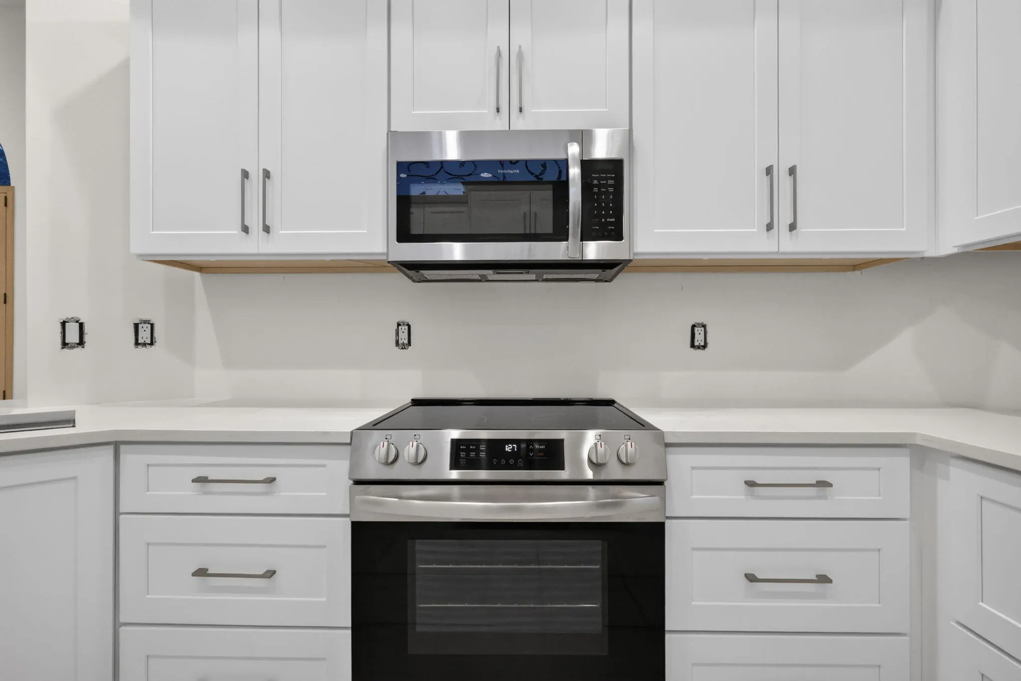 White shaker-style cabinetry with matte hardware, stainless steel range, and built-in microwave