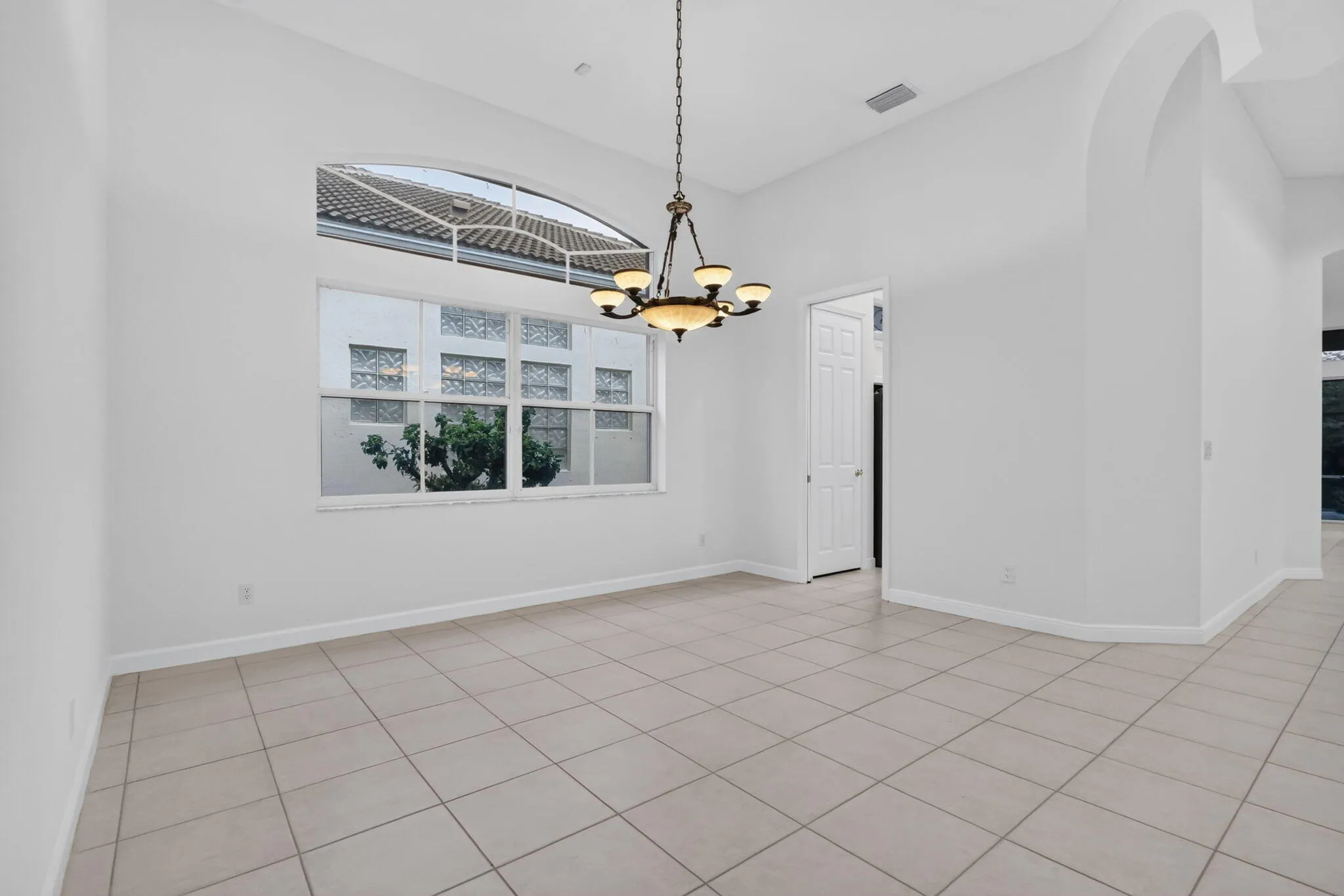 High ceilings with an arched transom window, a chandelier, and square tile flooring