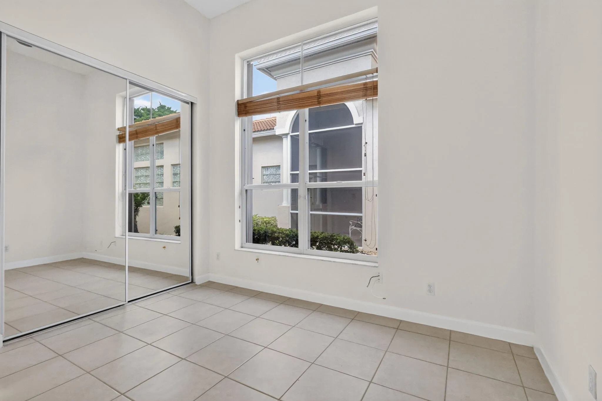 Vaulted ceiling with a large window, tile flooring, and mirrored closet doors