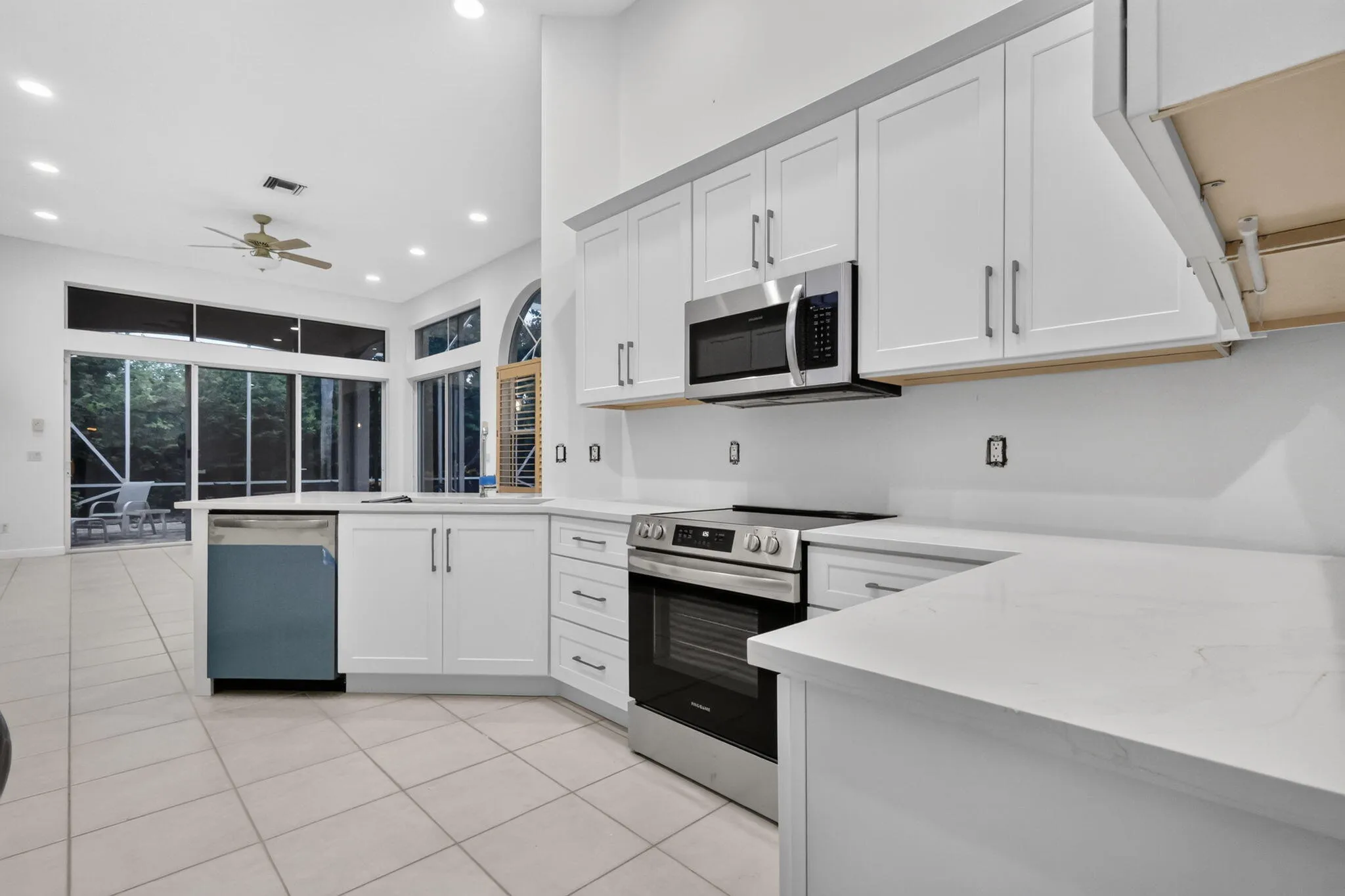 White cabinetry with stainless steel appliances, light-toned countertops, and recessed lighting