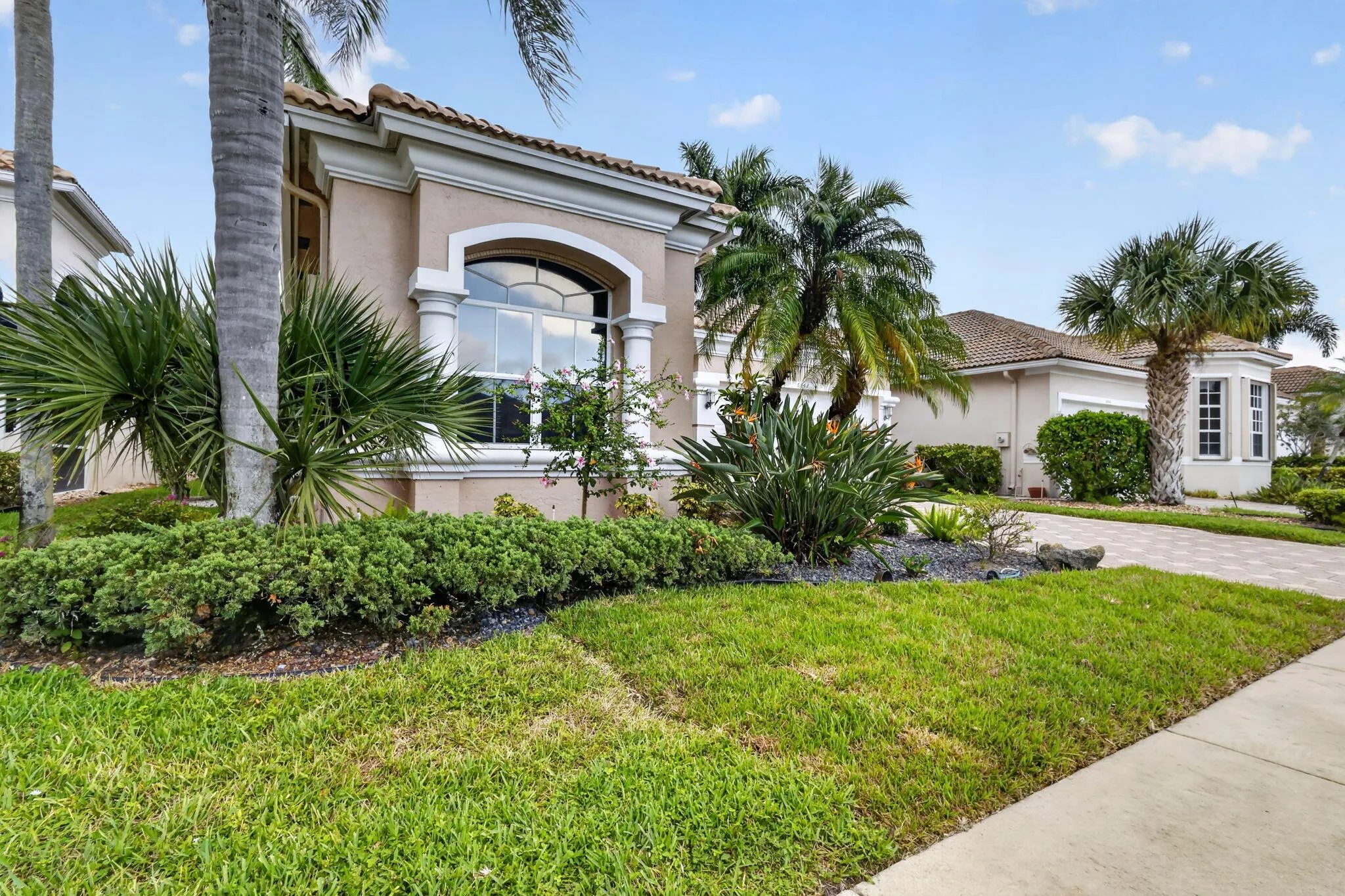 Stucco exterior with an arched window, decorative columns, and a tile roof