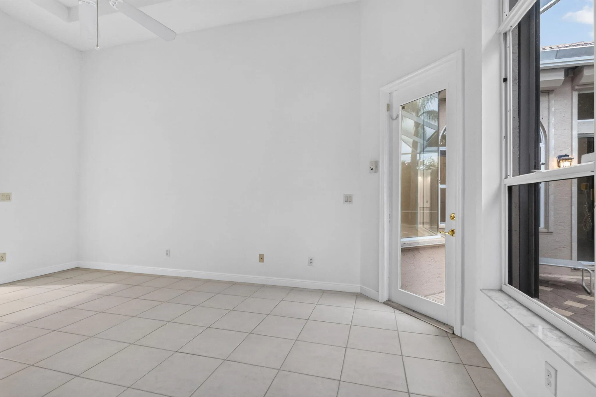Tile flooring with a full-light door, transom window, and ceiling fan