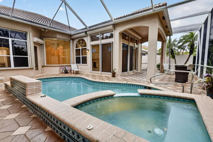 Screened outdoor living area featuring a custom-shaped pool with integrated spa