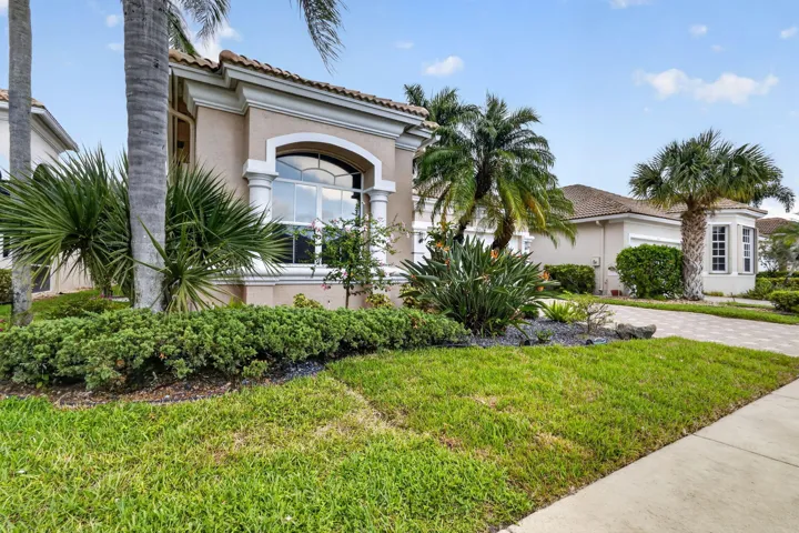 Stucco exterior with an arched window, decorative columns, and a tile roof