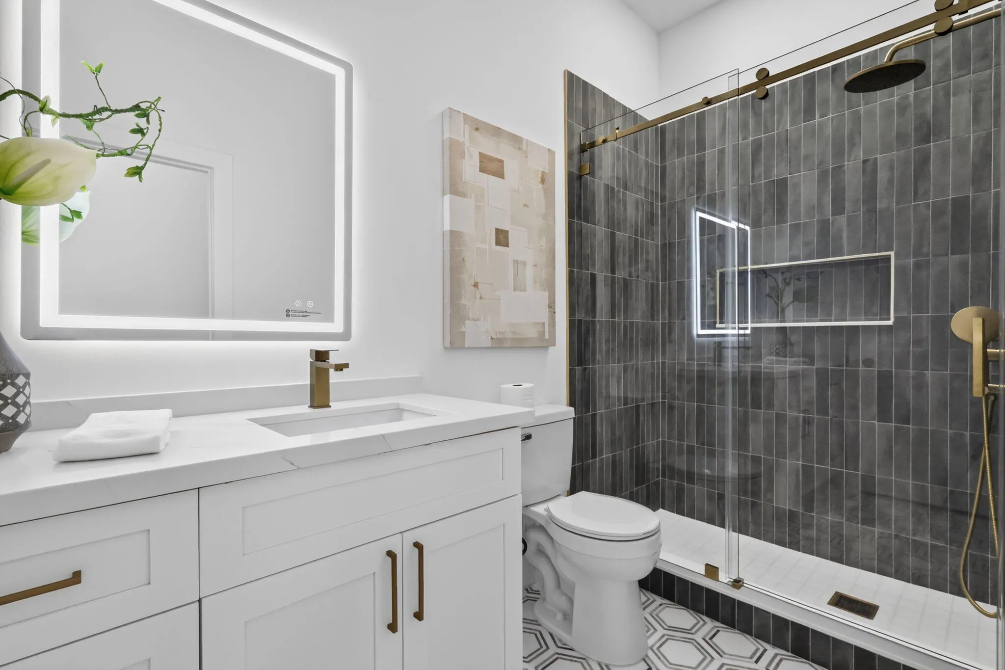 Bathroom featuring a white vanity with integrated sink, illuminated mirror, and brass-finish fixtures