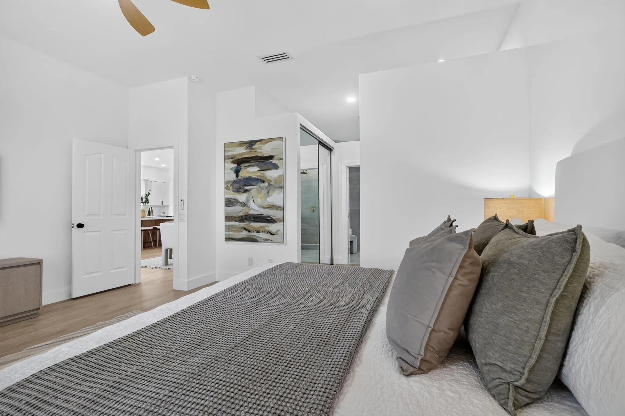 Vaulted ceiling with a ceiling fan, light wood-finish flooring, white paneled interior doors, and a sliding glass shower enclosure