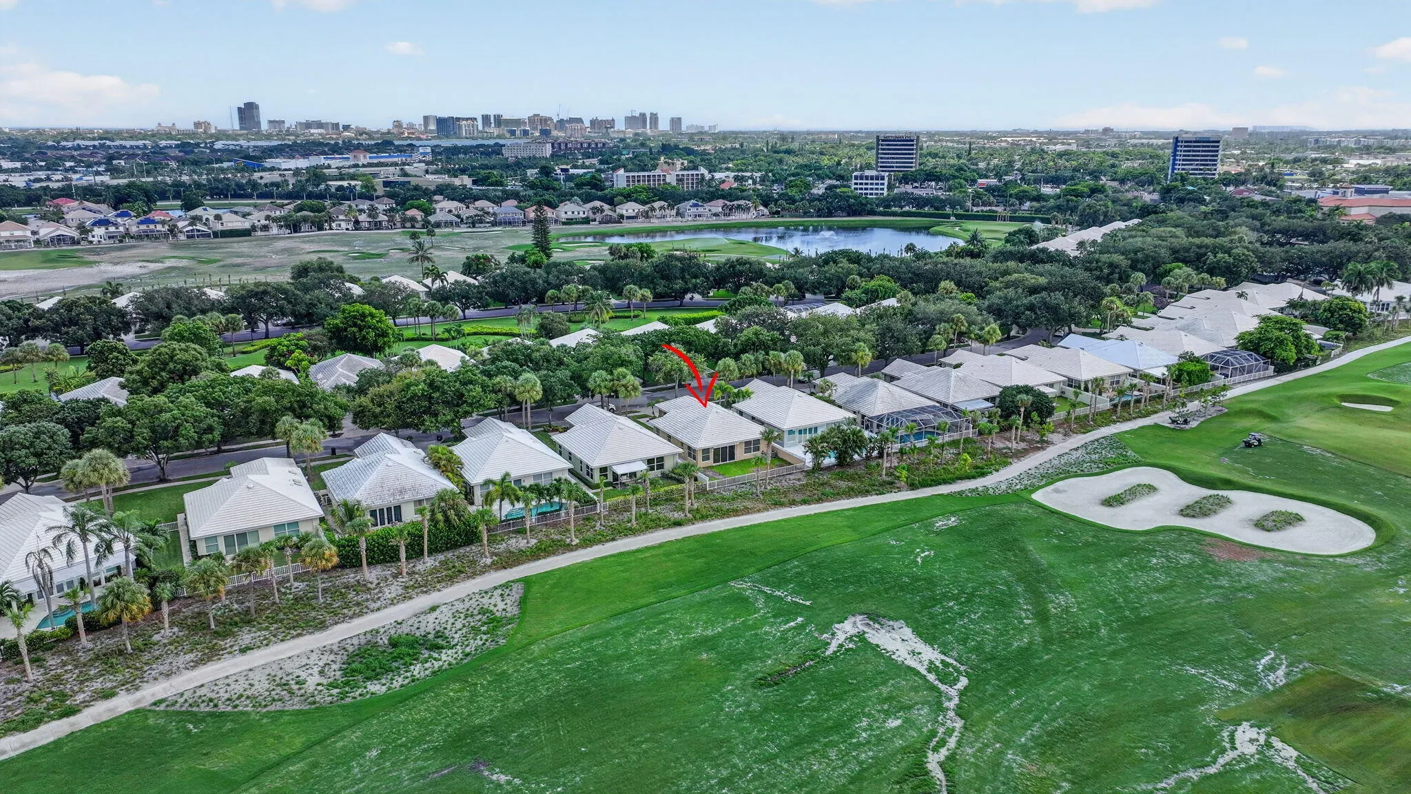 Lush green golf course setting with mature trees and a distant urban skyline