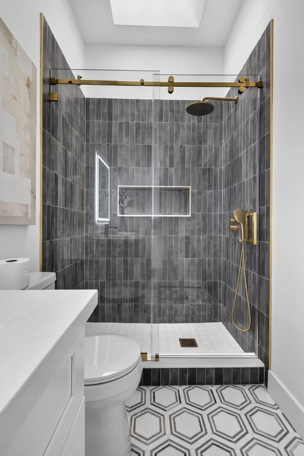 Walk-in shower with dark tile surround, gold-finish fixtures, and a glass enclosure