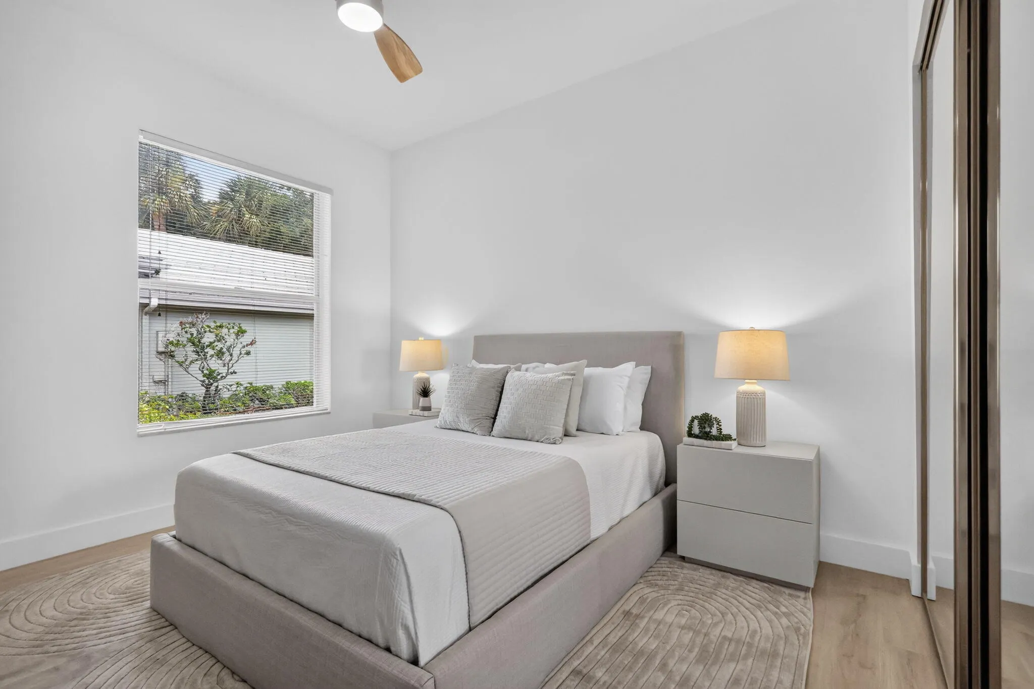 Recessed window, wood-finish flooring, ceiling fan, mirrored closet doors, and a neutral color palette