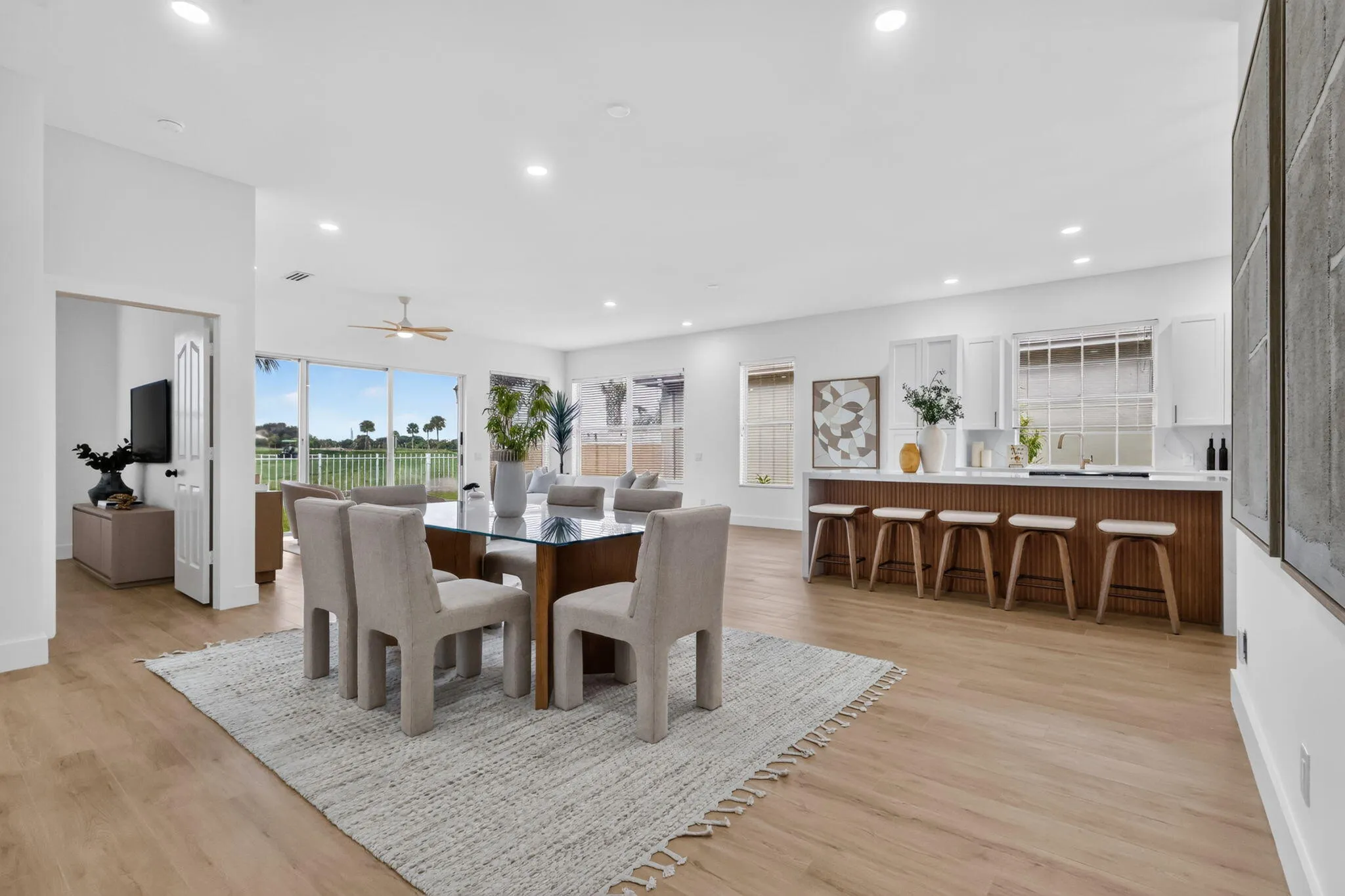 Open-concept living area featuring wood-finish flooring, recessed lighting, and a white kitchen with a peninsula island