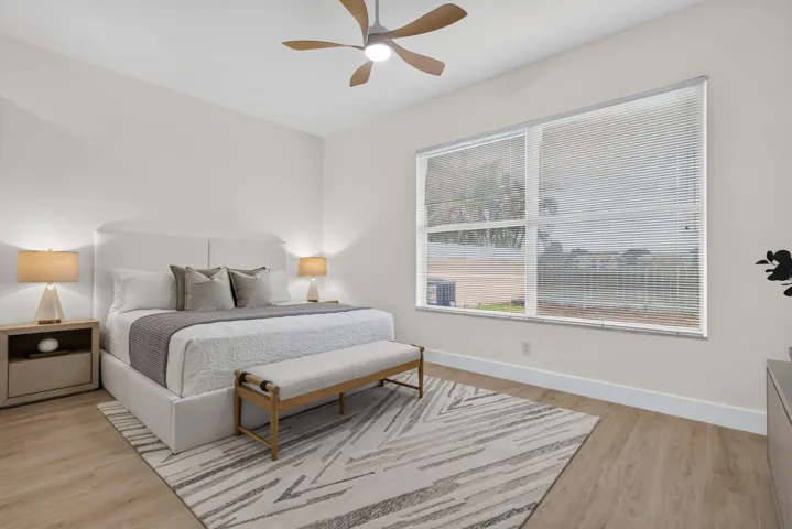 Spacious interior featuring a large window, light-toned wood-finish flooring, and a contemporary ceiling fan