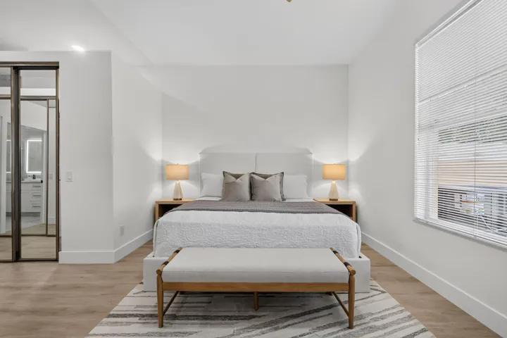 Wood-finish flooring, white walls, large window with blinds, recessed ceiling lighting, and sliding glass-paneled room divider