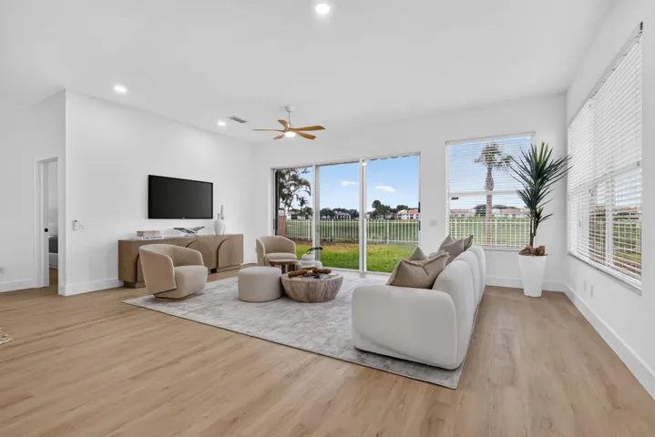 Spacious living area featuring wood-finish flooring, recessed lighting, a ceiling fan, and large sliding glass doors leading to the exterior