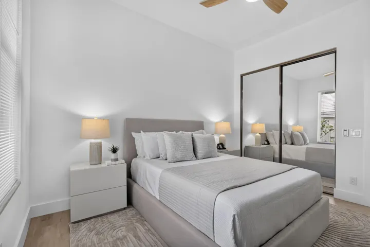 Light wood-finish flooring, mirrored closet doors, a ceiling fan, and white window blinds